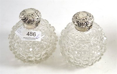 Lot 486 - A pair of Edwardian cut glass scent bottles with foliate embossed silver covers, Birmingham 1903