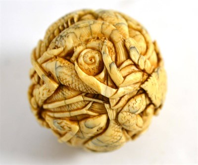 Lot 491 - A Japanese carved ivory ball, circa 1920, depicting a myriad of fish and sea creatures...