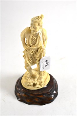 Lot 492 - A Japanese Meiji period okimono of a fisherman (one piece carving) with carved wood stand