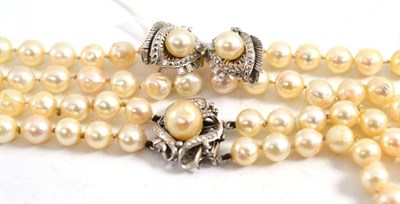 Lot 25 - A two row cultured pearl necklace, with an Art Deco style clasp stamped '14K' and a pair of...