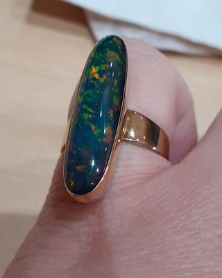 Lot 2073 - A Black Opal Ring the oval cabochon black opal...