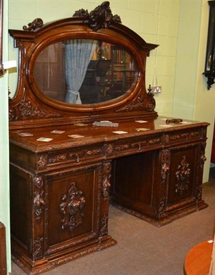 Lot 411 - A Victorian oak pedestal sideboard with oval mirrored back, decorated profusely with foliate carved