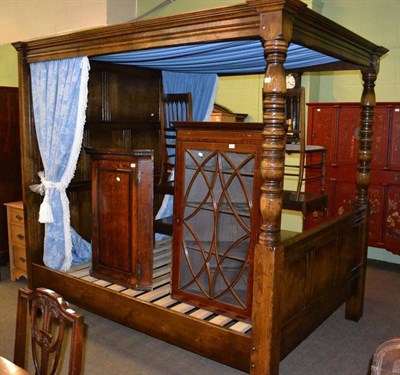 Lot 424 - A reproduction panelled oak four poster bed with drapes