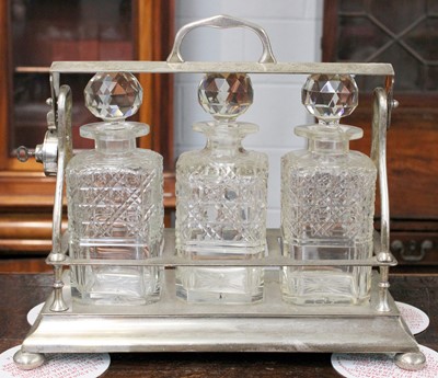 Lot 157 - A Silver-Plated Three Bottle Tantalus on Bun...