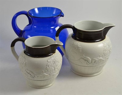 Lot 68 - Two 19th century relief decorated hunting jugs and a blue glass jug