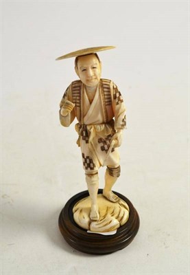 Lot 100 - A Japanese Meji carved ivory okimono of a man holding a sickle, on a wooden base