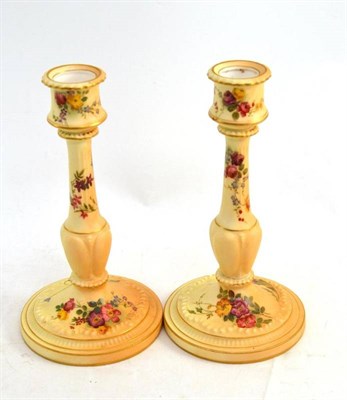 Lot 69 - A pair of Royal Worcester blush ivory candlesticks, each printed and painted with flowers, 21cm