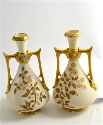 Lot 261 - A pair of Royal Worcester ivory ground vases with tapering neck and broad gilt angular handles,...