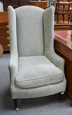 Lot 1271 - A High Back Wing Chair, on ebonised supports,...