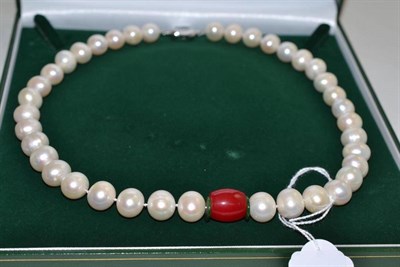 Lot 336 - A cultured pearl necklace with a red stone and two green barrel spacers