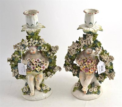 Lot 404 - A pair of Derby porcelain figural chambersticks, circa 1770, each as a putto sitting in a...