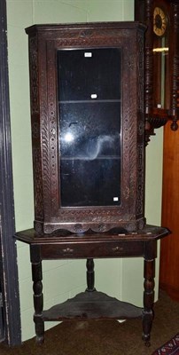 Lot 651 - A carved oak corner cabinet and an oak corner table