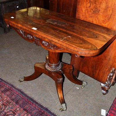 Lot 667 - A George IV rosewood foldover tea table, with rounded rectangular top, on brass caps and castors