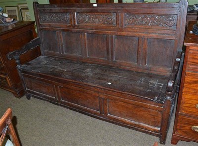 Lot 782 - An 18th century joined oak settle with a carved frieze and hinged box seat