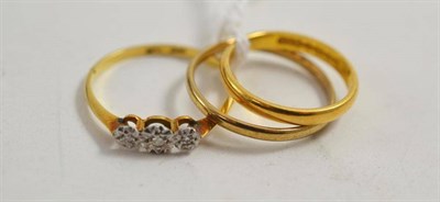 Lot 63 - A 22ct gold band ring, a 9ct gold band ring and a diamond three stone ring stamped '18CT' and...
