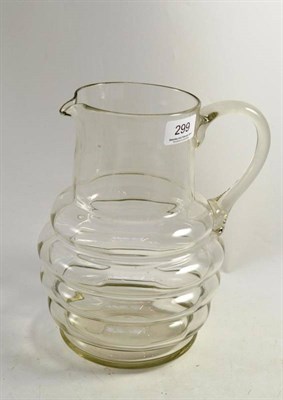 Lot 299 - A glass water jug, early 19th century, the ribbed oval body with cylindrical neck and loop...