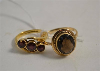 Lot 314 - An 18ct gold garnet three stone ring and a 9ct gold smokey quartz ring