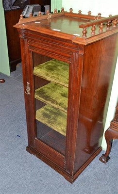 Lot 440 - A walnut music cabinet with carved back rail and glazed door