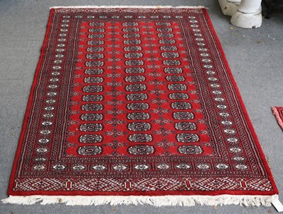 Lot 1235 - "Bukhara" Rug, the cherry red field with three...