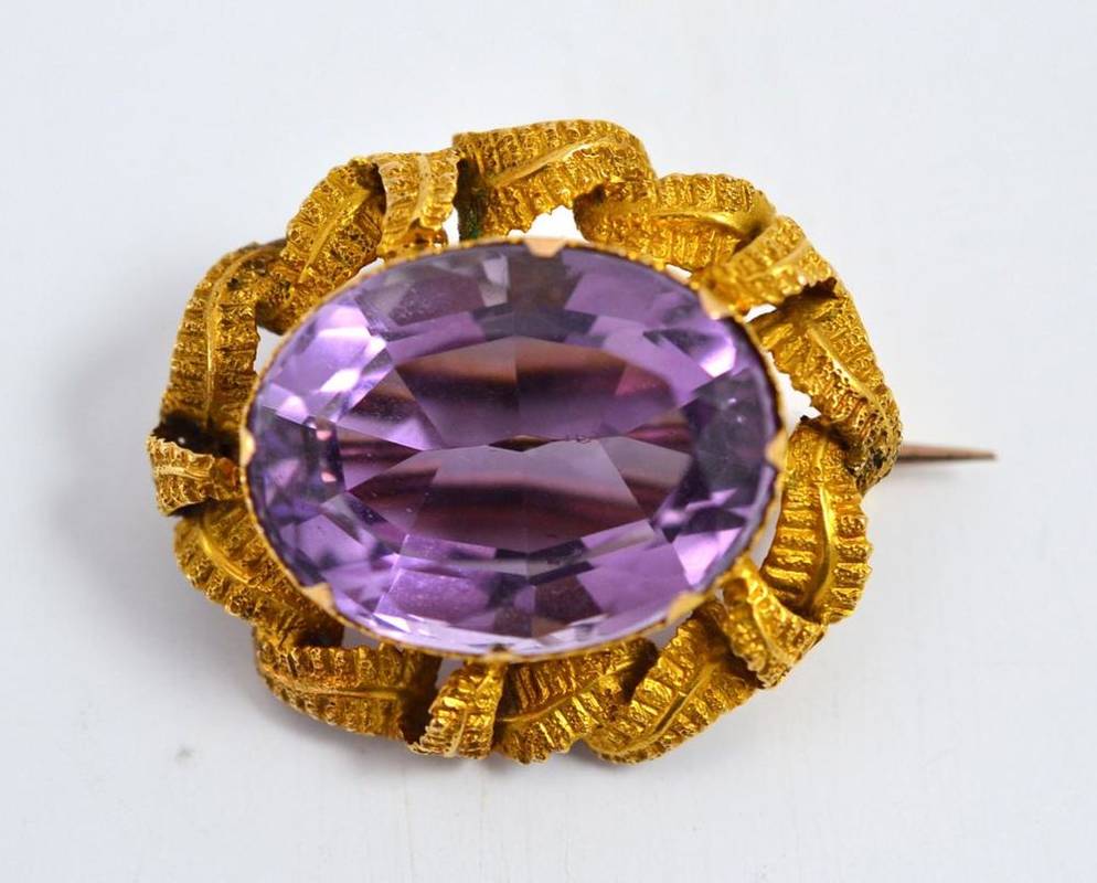 Lot 27 - An amethyst brooch, the oval mixed cut amethyst within a claw tipped bezel setting with...
