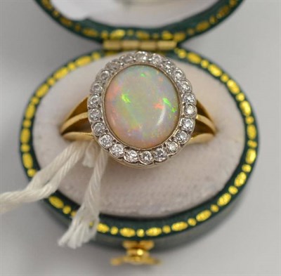 Lot 178 - An opal and diamond ring, the oval cabochon opal within a border of twenty-two old cut diamonds, in