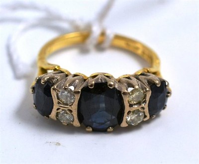 Lot 193 - An 18ct gold sapphire and diamond ring, three graduated oval mixed cut sapphires spaced by pairs of