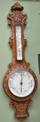 Lot 439 - A Victorian carved oak aneroid barometer with thermometer