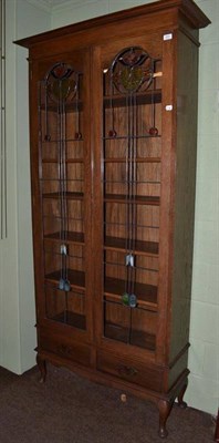 Lot 690 - An Arts and Crafts glazed oak bookcase with stained glass panels