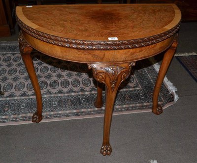 Lot 742 - A reproduction burr walnut veneered demi lune fold over card table with paw feet