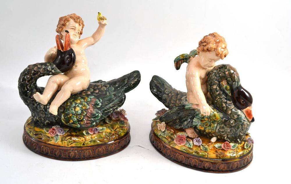 Lot 16 - A pair of late 19th/early 20th century Majolica figural groups, modelled as a cherub on a swan (2)