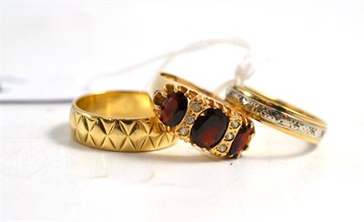Lot 102 - A 9ct gold patterned band ring, a 9ct gold garnet ring and an eternity ring