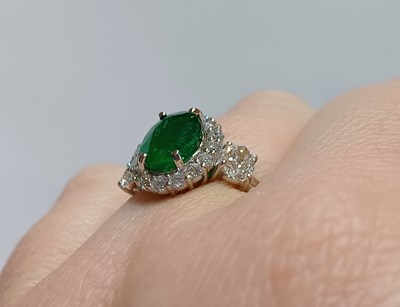 Lot 2230 - An Emerald and Diamond Cluster Ring the oval...