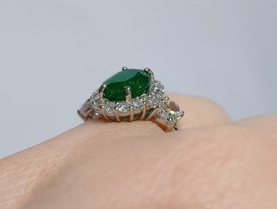 Lot 2230 - An Emerald and Diamond Cluster Ring the oval...