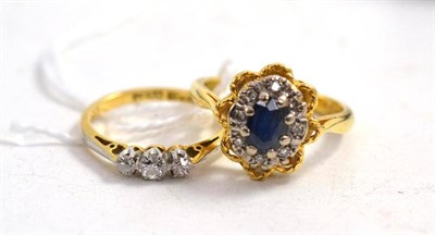 Lot 93 - An 18ct gold sapphire and diamond cluster ring, and a diamond three stone ring