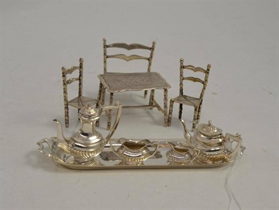 Lot 422 - A miniature silver four piece tea set and a tray, three miniature chairs and a table