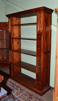 Lot 508 - A reproduction carved hard wood open shelf unit enclosed by drawers