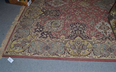 Lot 687 - Machine made carpet of Oriental design, the rust field with a medallion framed by palmette borders