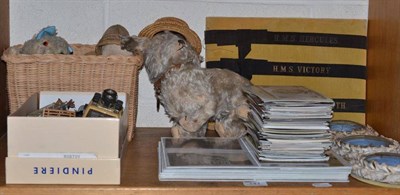 Lot 141 - A shelf including HMS ribbons, postcards, Diecast toys, shell nautical pictures, etc