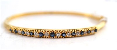 Lot 241 - A diamond and sapphire bangle stamped '750'