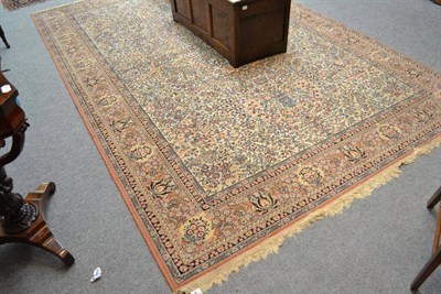 Lot 468 - Machine made carpet of oriental design, the ivory field of floral vines enclosed by palmette...