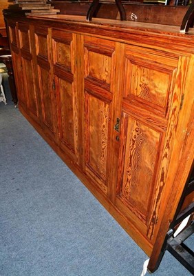 Lot 546 - A large pitch pine standing cupboard with three pairs of doors enclosing a shelved interior