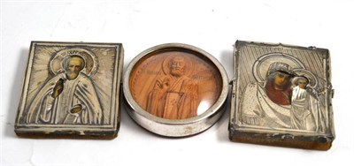 Lot 282 - Two miniature white metal mounted icons and a carved wood example in a circular frame (3)