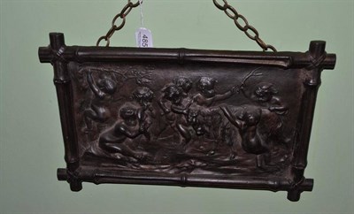 Lot 485 - A cast iron plaque depicting eight cherubs frolicking with a ram, in a cast iron simulated...