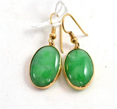 Lot 70 - A pair of Chinese jade earrings of apple green cabochons in gold settings, marked 18ct, circa 1925