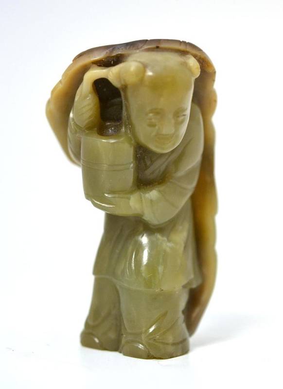 Lot 230 - A Chinese Celadon Jade Figure of a Boy, standing holding a vase, sheltering under a deer skin,...