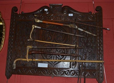 Lot 871 - Seven various riding crops and canes on an oak whip rack