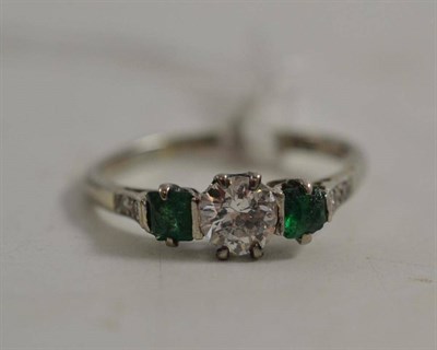 Lot 52 - A diamond and emerald three stone ring, a round brilliant cut diamond between two square step...