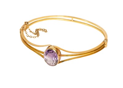 Lot 91 - An Amethyst Bangle, the central oval cut...