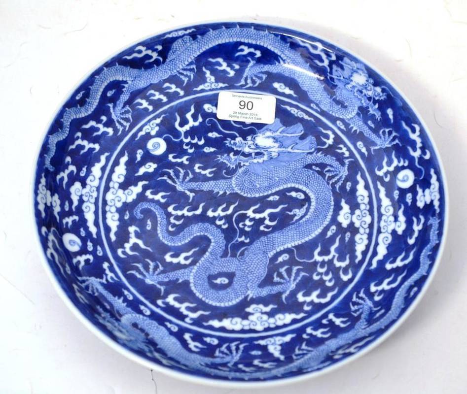 Lot 90 - A Chinese Saucer Dish, decorated in underglaze blue, with dragons amongst cloud scrolls chasing...