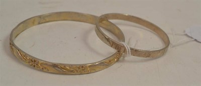 Lot 295 - Two bangles - one a child's with lined decoration and a crest style stamp, the other an adult's...